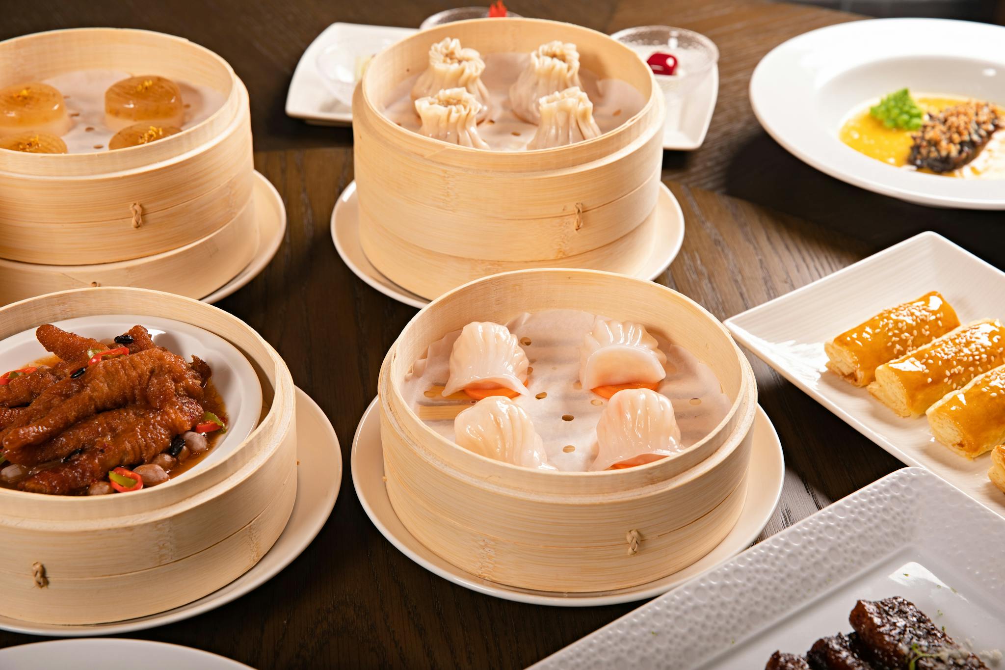 A delectable assortment of Chinese dim sum, including dumplings and chicken feet, served in bamboo steamers on a dining table.