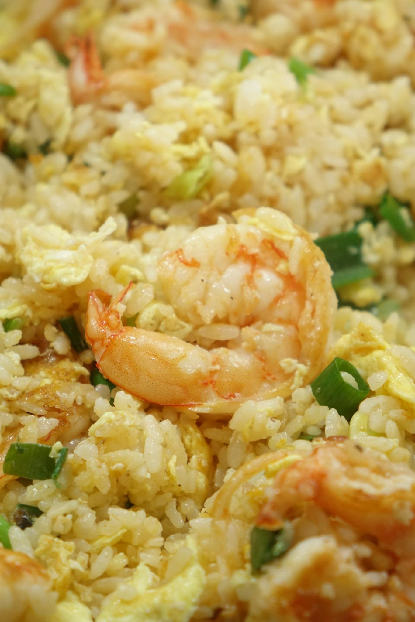 Close-up of appetizing shrimp fried rice with eggs and scallions.