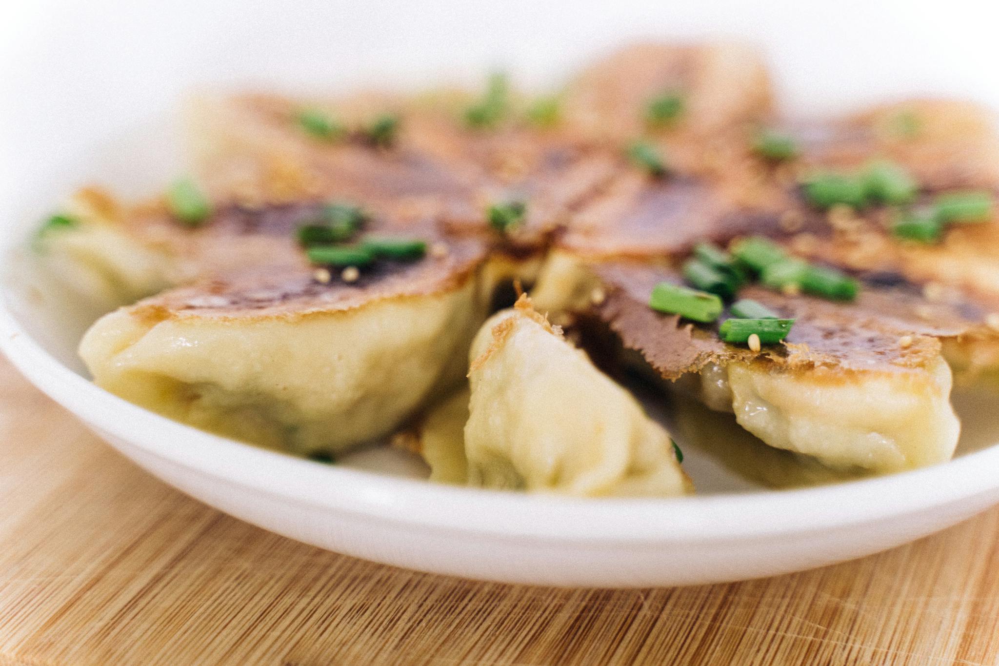Delicious crispy dumplings garnished with green onions on a white plate.