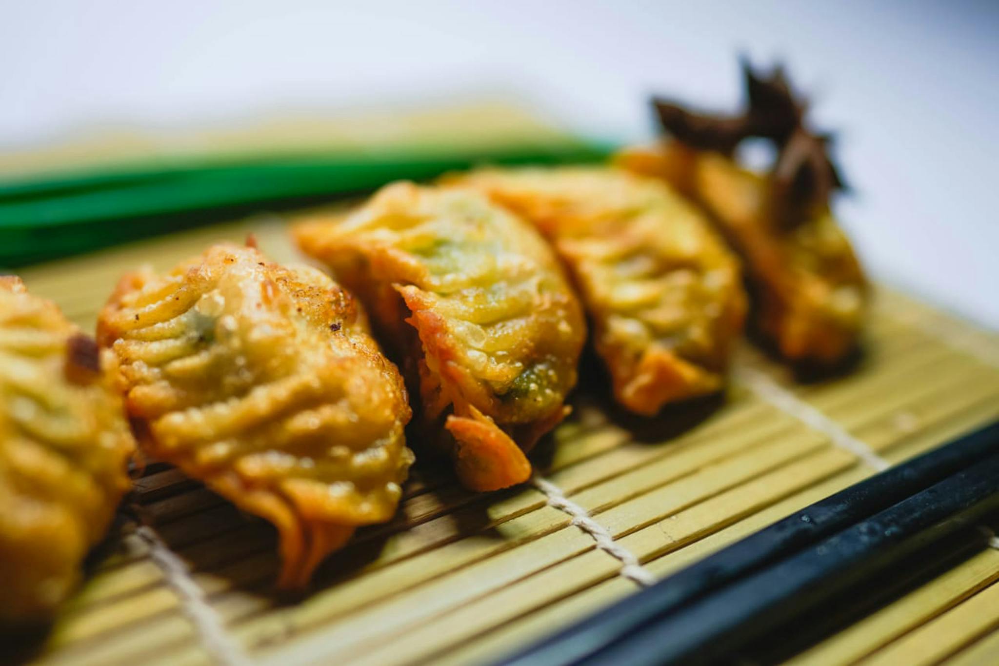Delicious fried gyoza dumplings arranged on a bamboo mat with chopsticks nearby.