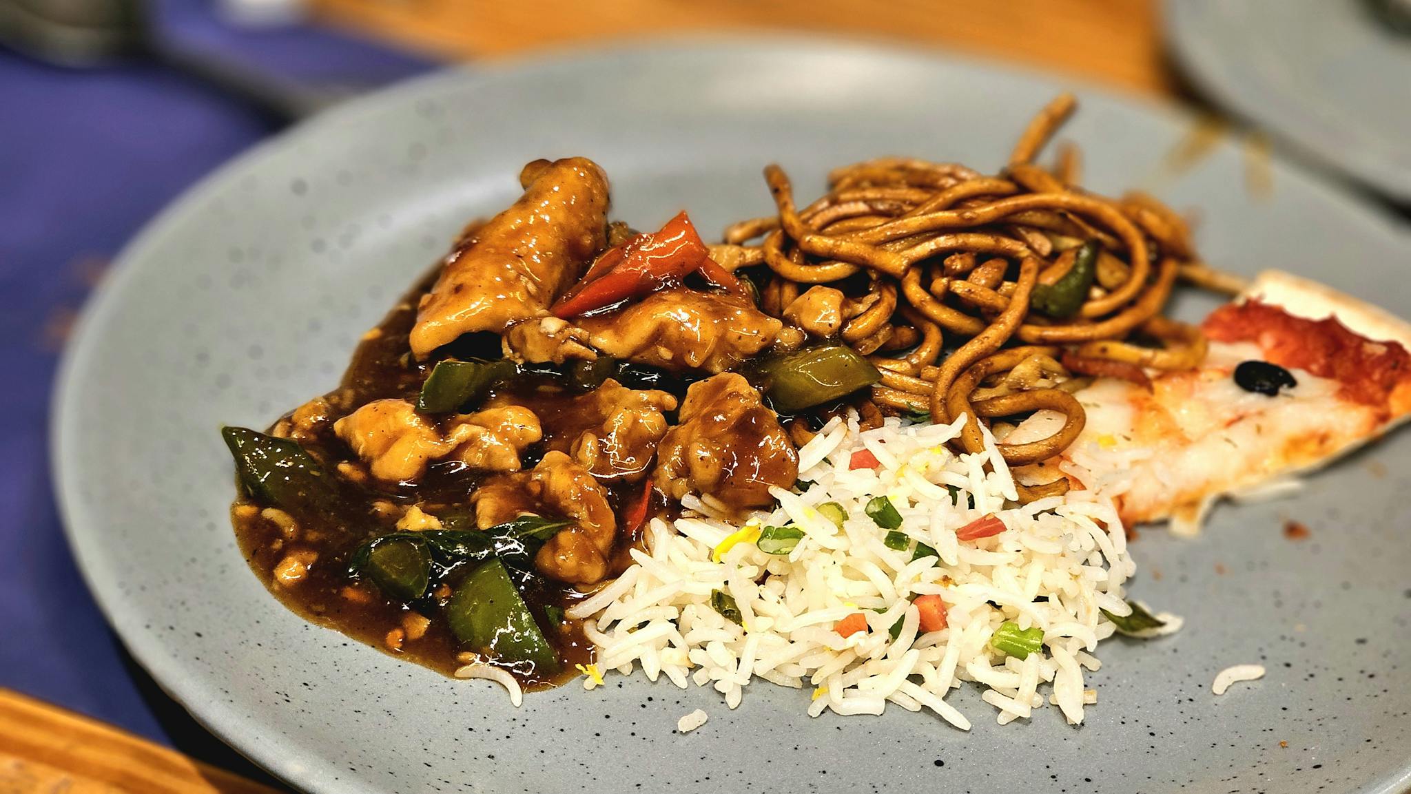Tantalizing Asian fusion meal featuring spicy noodles, fried rice, and stir-fried chicken on a plate.